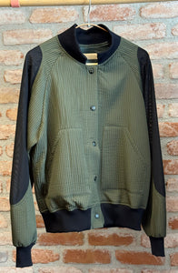 Green and black jacket hanging against a brick wall